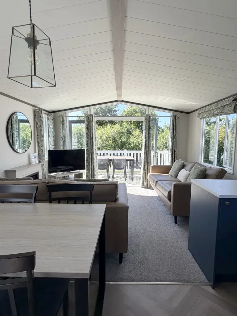 The living room of a Gold Caravan at Gilsland Park, with doors to the deck